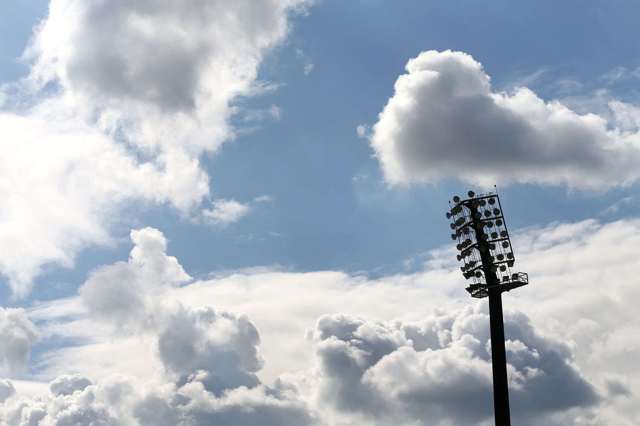 Football field lights against a cloudy sky